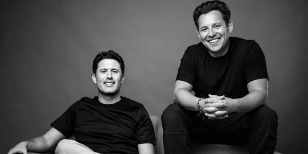 A black-and-white portrait of Harley Finkelstein and David Segal sitting casually on a couch.